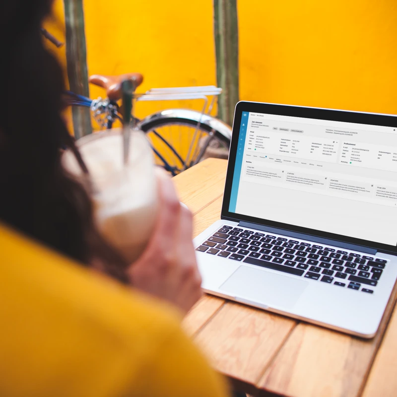 over-shoulder-mockup-of-a-woman-using-a-macbook-on-a-wooden-table.png